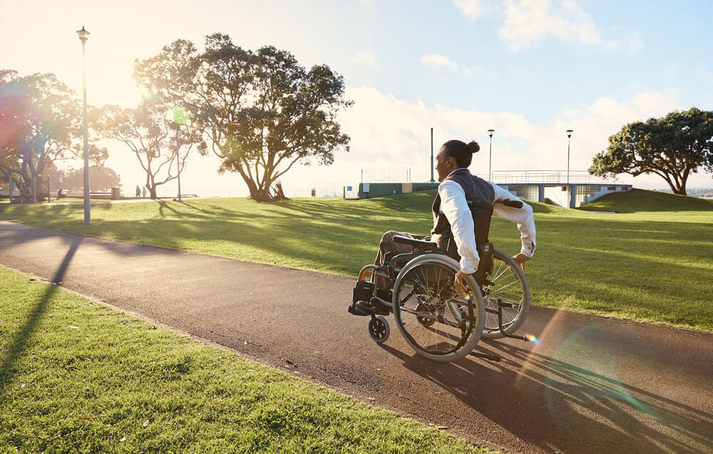 A person using a properly fitted manual wheelchair in an outdoor park, showing good posture and smooth self-propulsion.