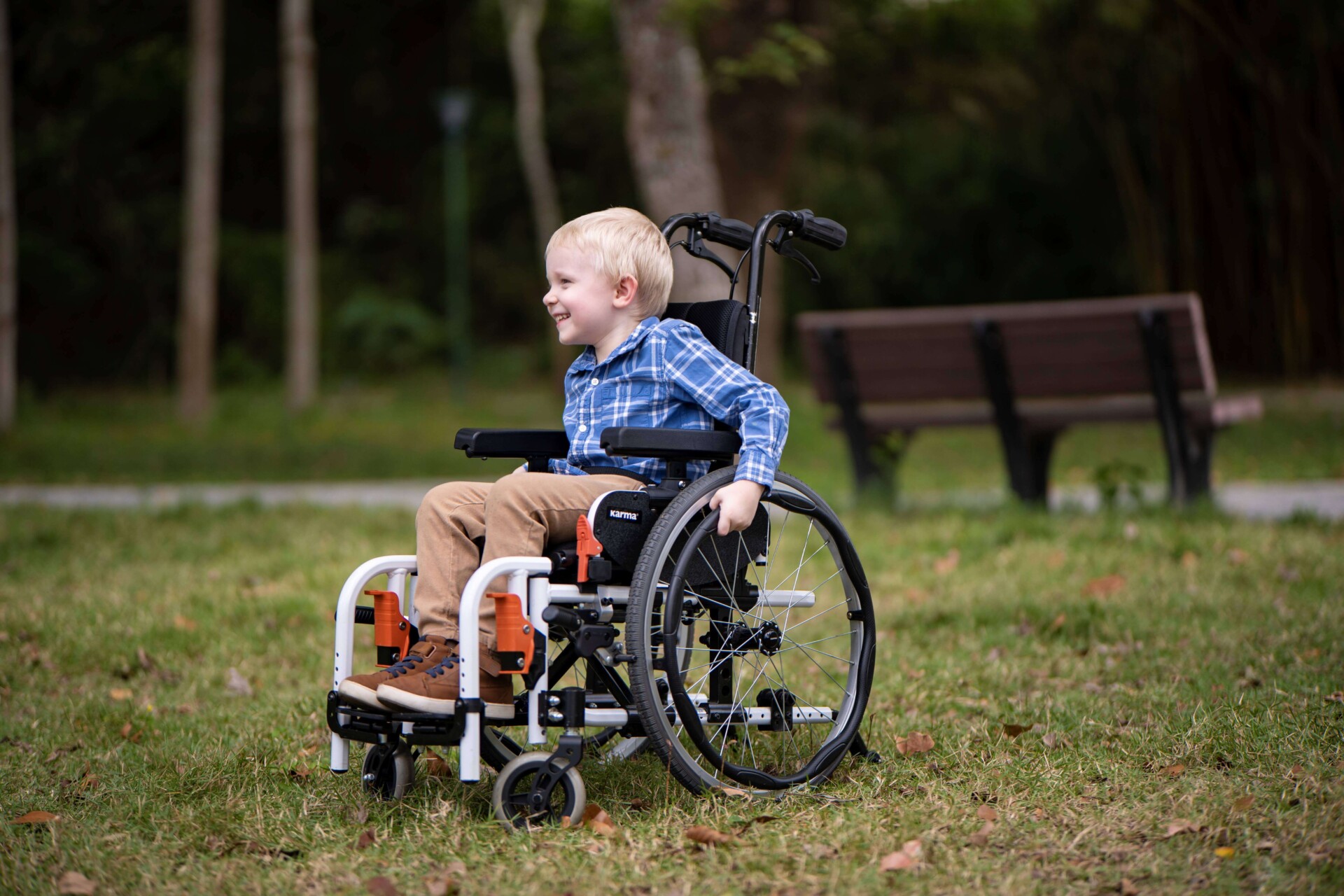 A-kid-in-a-pediatric-wheelchair-propelling-himself-around-in-a-park