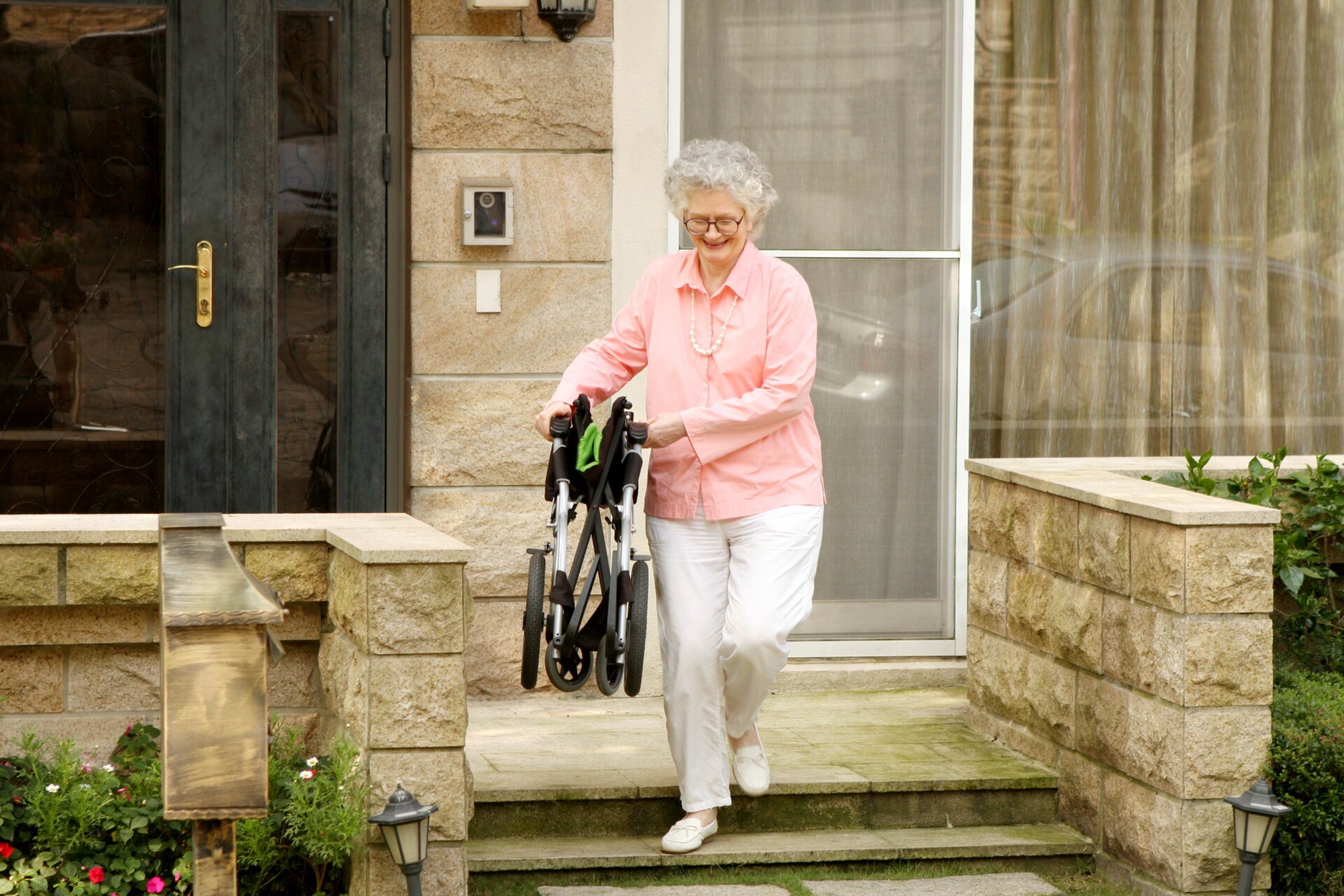 An-elderly-woman-carrying-a-foldable-munual-wheelchair-walking-downstairs