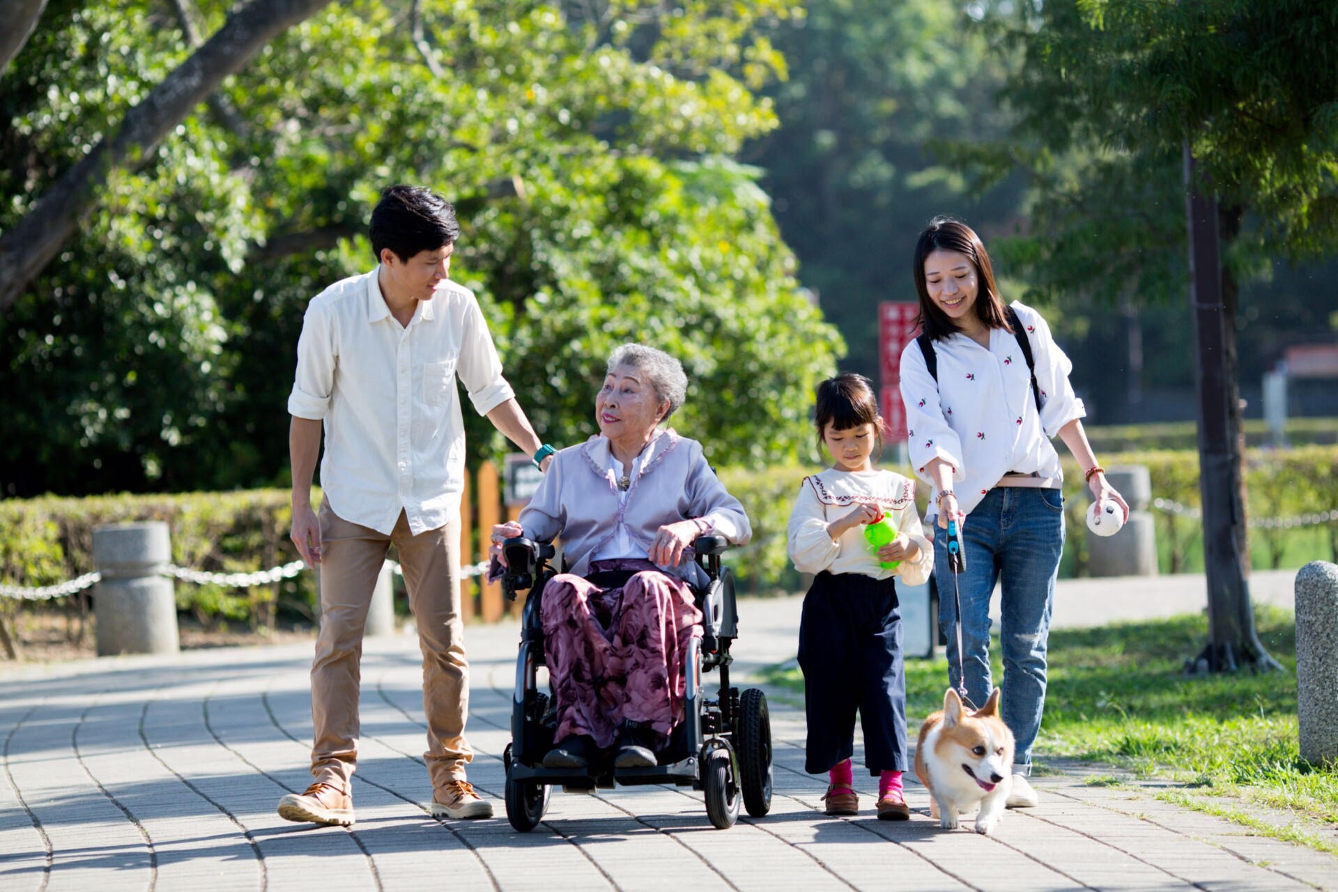 An-elder-in-a-travel-power-wheelchair-going-around-the-park-with-her-family 