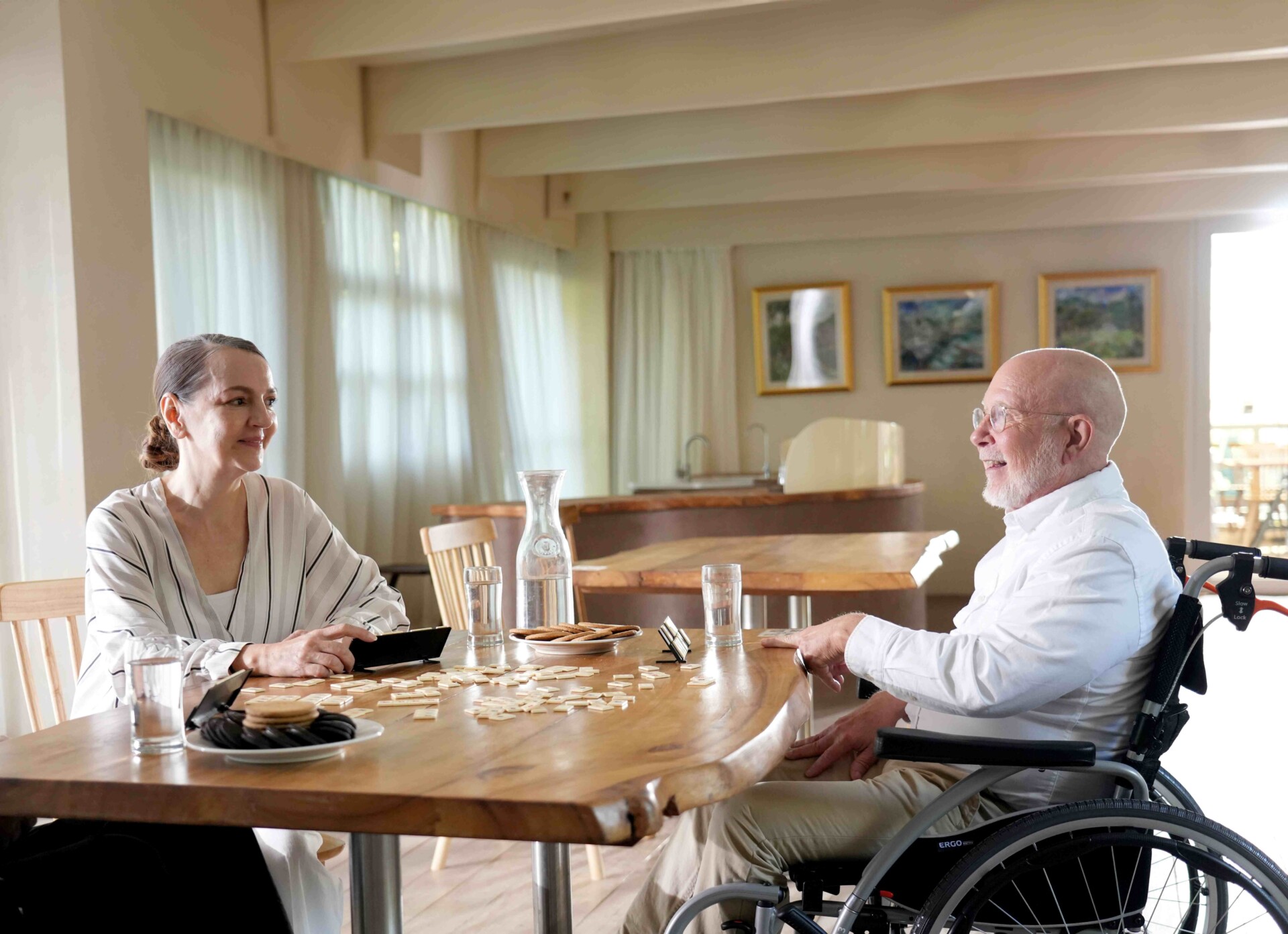 Man in wheelchair chatting with friend across the table.