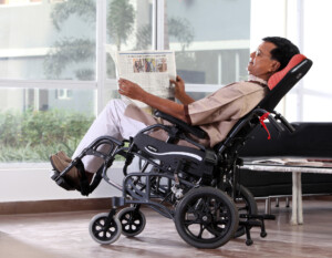 A man reading comfortably in a tilt-in-space wheelchair.
