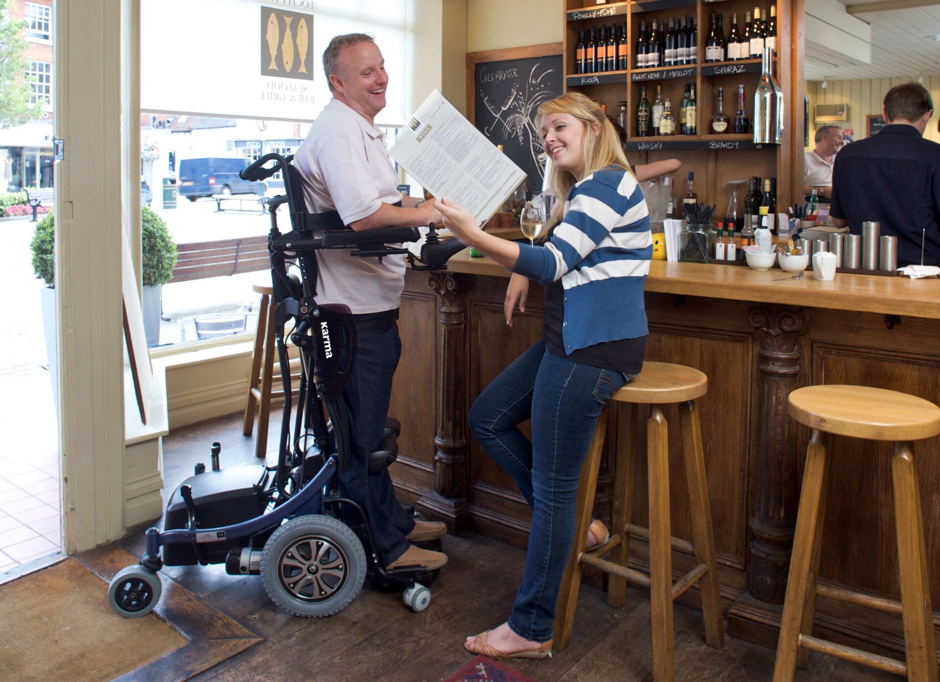 A-man-in-a-standing-wheelchair-smiling-and-chatting-with-a-woman
