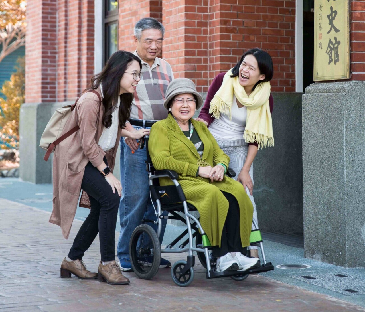 An-elder-lady-in-a-wheelchair-surrounded-by-her-family-in-the-front-of-a-building